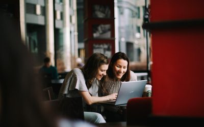 woman in white shirt using macbook